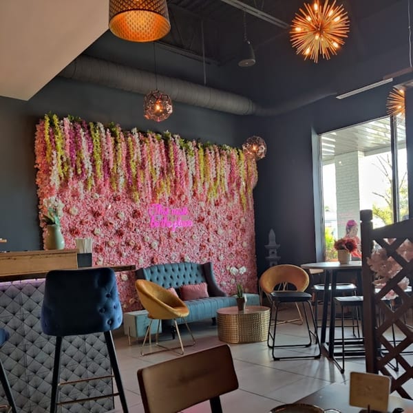 Akeno Sushi Bar and Thai's dining area with a pink floral wall, blue sofa, and modern lighting.