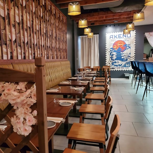 Akeno Sushi Bar and Thai dining room with wooden tables, chairs, and a large Japanese-themed mural.
