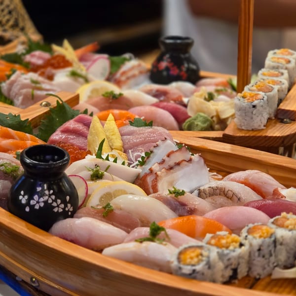 A large wooden boat filled with a colorful assortment of sushi, sashimi, and rolls.