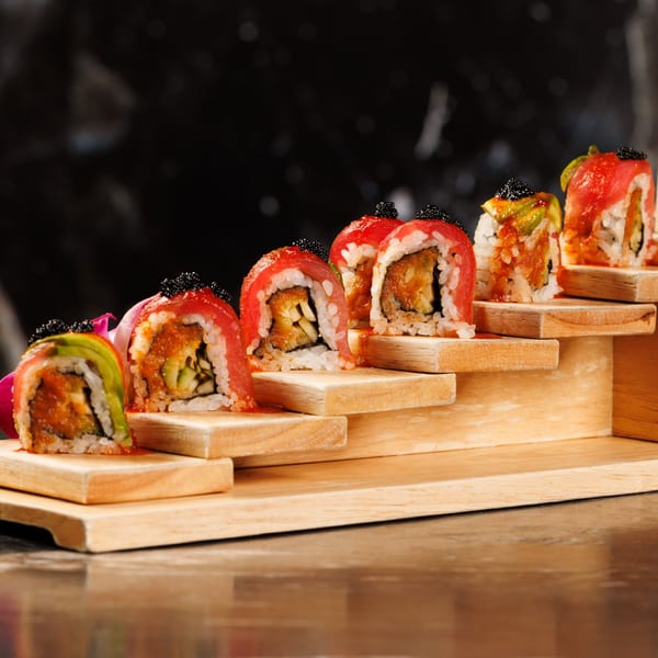 Akeno Sushi Bar and Thai's tuna sushi rolls with black caviar on a tiered wooden stand.
